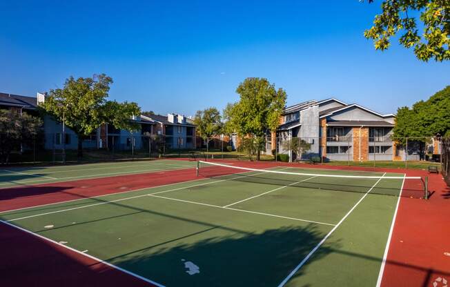 a tennis court with apartments in the background