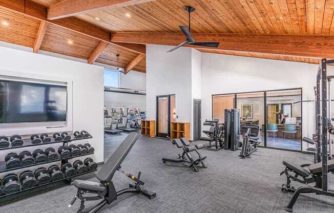 A spacious home gym with a variety of equipment including dumbbells, weight machines, and a bench press.