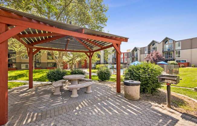 A patio with a table and benches under a pergola.