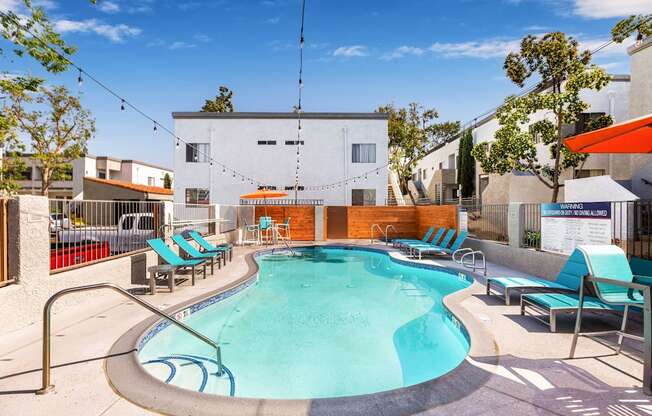 Dog-Friendly Apartments in Colton, CA- Ardella at Reche Canyon - Sparkling Pool Surrounded By Lounge Chairs and Views of the Apartment Homes