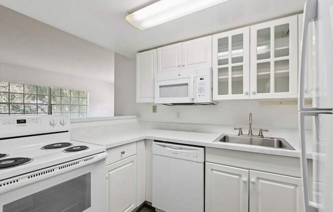 A white kitchen with a stove, dishwasher, and microwave.
