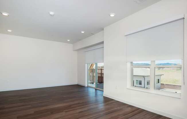 a living room with white walls and a large window at The Crossings at Windsong, Prescott Valley, 86314