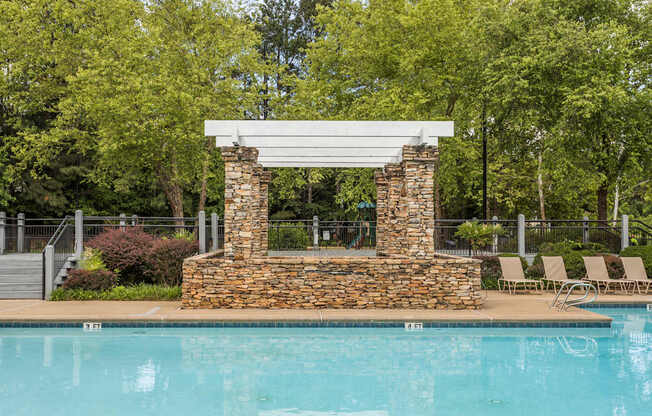 A pool with a stone pillar and a white roof.