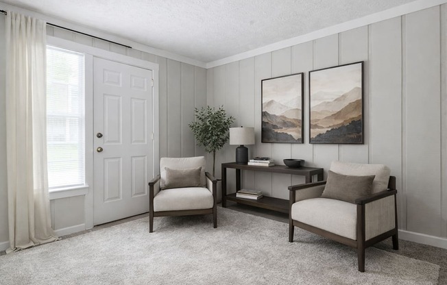 A living room with a chair, a table, and two pictures on the wall.