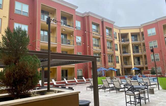 a courtyard with a pool and lounge chairs in front of an apartment building
