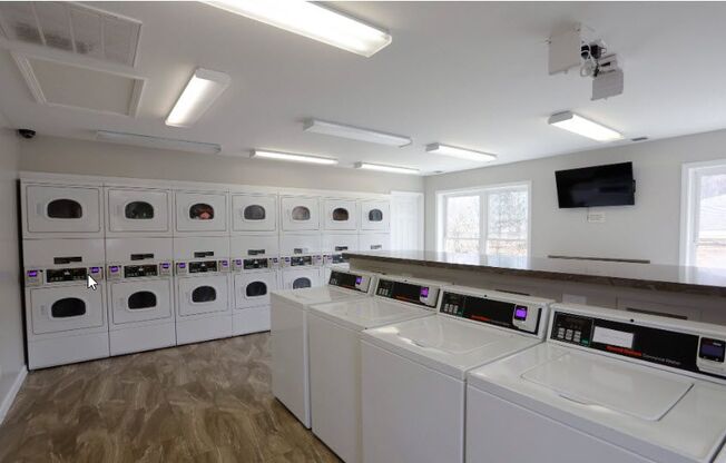 a laundry room with washers and dryers and a row of washing machines