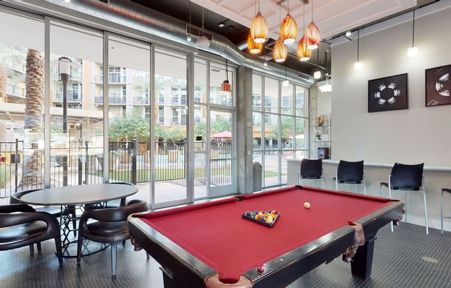 a red pool table in a room with large windows