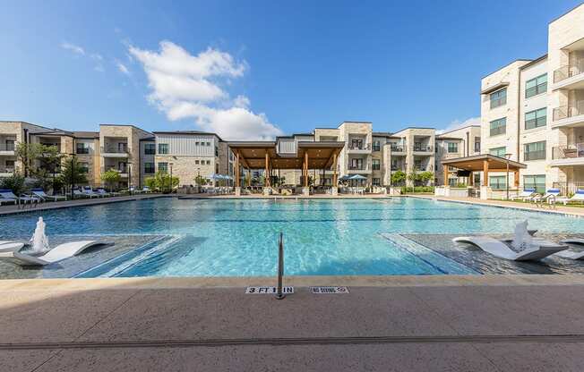 A large swimming pool in front of apartment buildings.