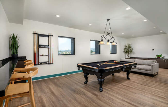 A pool table is in the middle of a room with a couch and a chair.