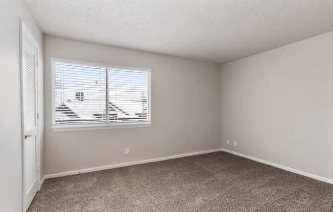 an empty bedroom with a window and carpeted floor at Eastwood Crossings, Missouri, 64129