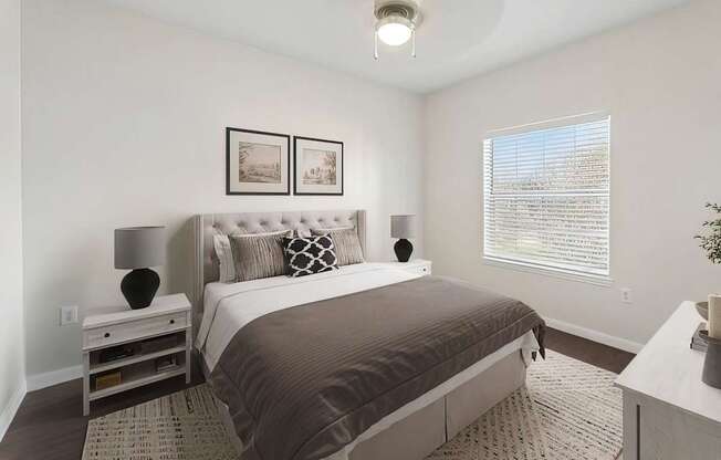 A bedroom with a large bed and a nightstand with a lamp.