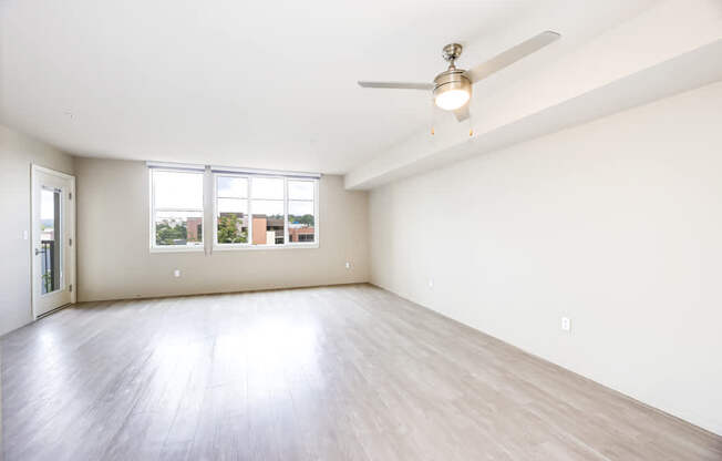 Empty room with a ceiling fan and wooden flooring.
