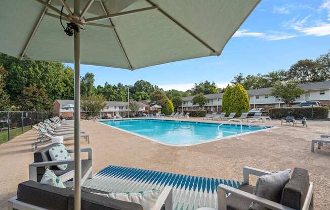 a swimming pool with chairs and an umbrella at a resort