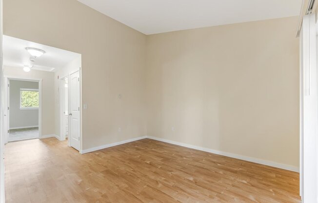 Empty room with wooden flooring and white walls.