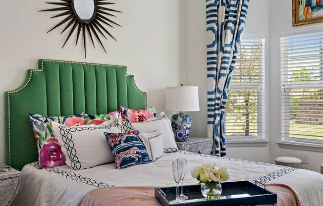 Two-Bedroom Apartments in San Marcos, TX-Sadler House-Bedroom-Green Headboard, Large Windows, Blue Drapes, Wall-to-Wall Carpet, and Grey Night Stand