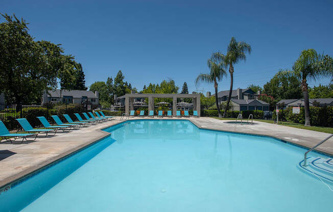 A large swimming pool with lounge chairs and a fountain in the middle.