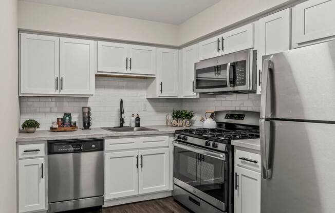 an empty kitchen with stainless steel appliances and white cabinets