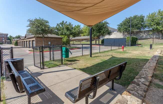 a park with benches and a fence and a tennis court