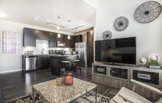 Living room space with television and coffee table, kitchen in background