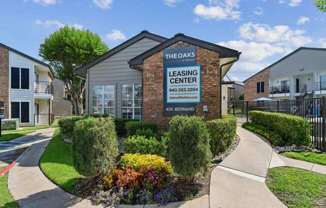 The Oaks of Denton Leasing Office is surrounded by paved paths and lush landscaping in Denton, TX