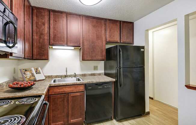 a kitchen with black appliances and wooden cabinets at Pheasant Park Apartments, New Hope, MN