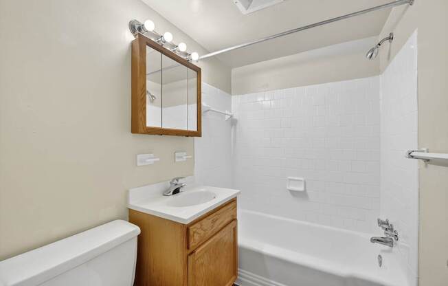 A bathroom with a white tub, sink, and mirror.