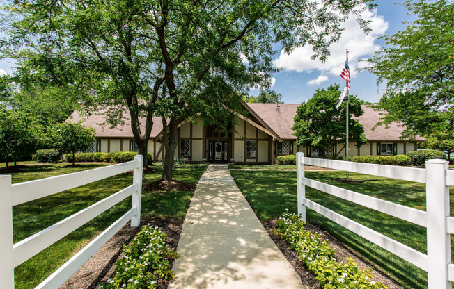 the front of a clubhouse with a white fence and a path leading up to it in Greenwood, Indiana