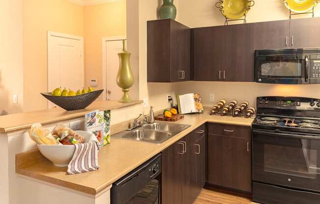 a kitchen with dark cabinets and a bowl of fruit on the counter