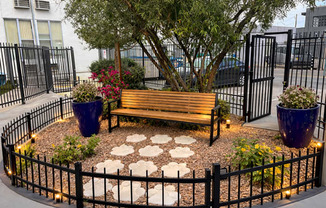 A small park with a bench, a tree, and flower pots.