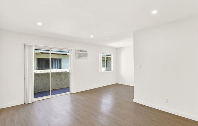 A room with a wooden floor and a doorway leading to a balcony.