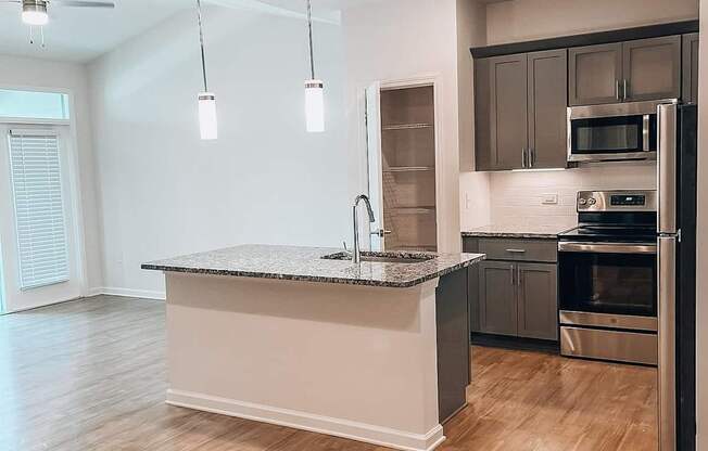 A modern kitchen with a granite countertop and stainless steel appliances.at Evolve at Parkway Apartment Homes, Concord