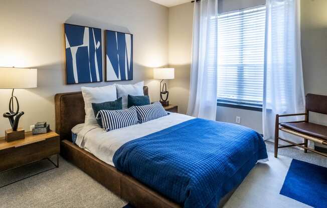 a bedroom with a bed and a window with a blue comforter