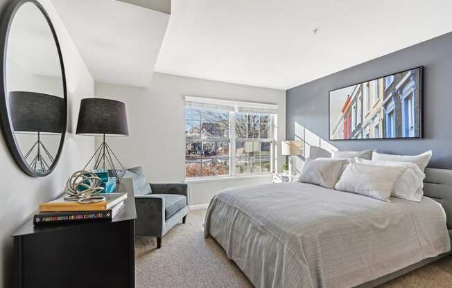 A bedroom with a large bed, a side table with a lamp, and a painting on the wall.