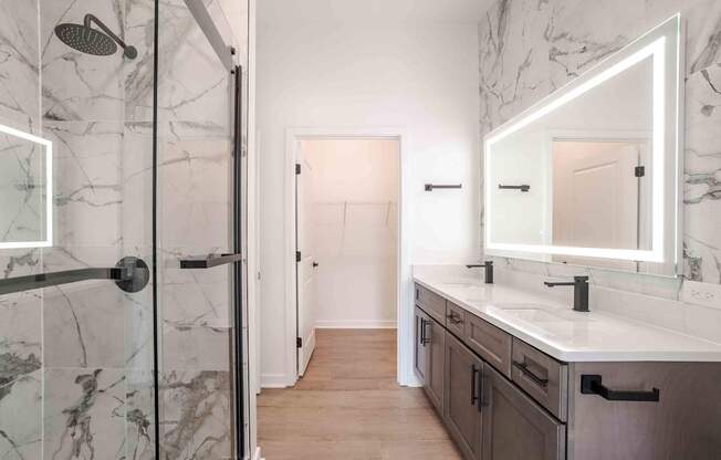 A bathroom with a marble shower and a white sink vanity.