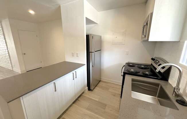 A kitchen with a stove, refrigerator, and sink.