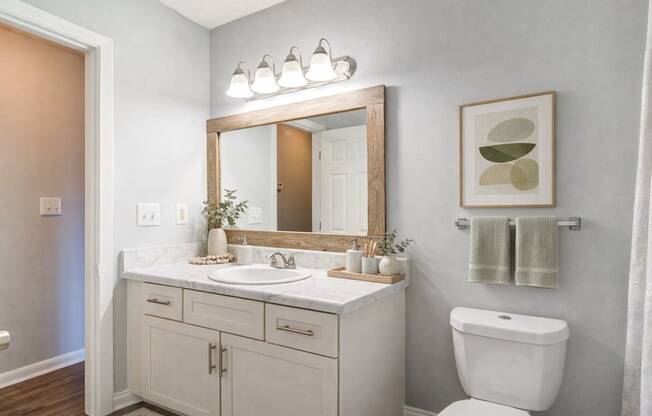 A bathroom with a white toilet, sink, and cabinets.