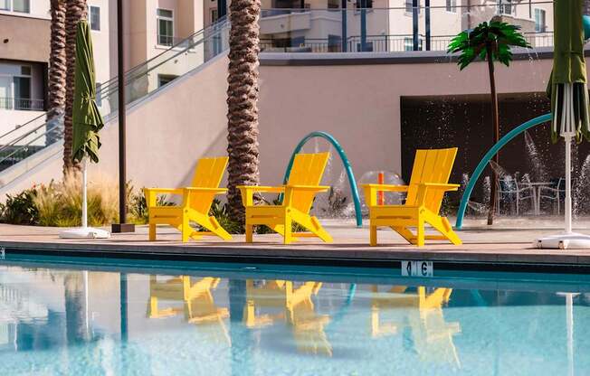 A pool with yellow chairs and a waterfall.