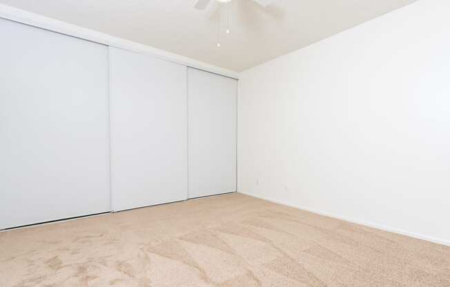 an empty room with white walls and flooring and a ceiling fan
