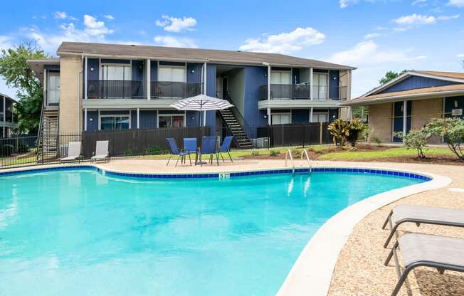 A swimming pool in front of a building with a blue sky in the background.