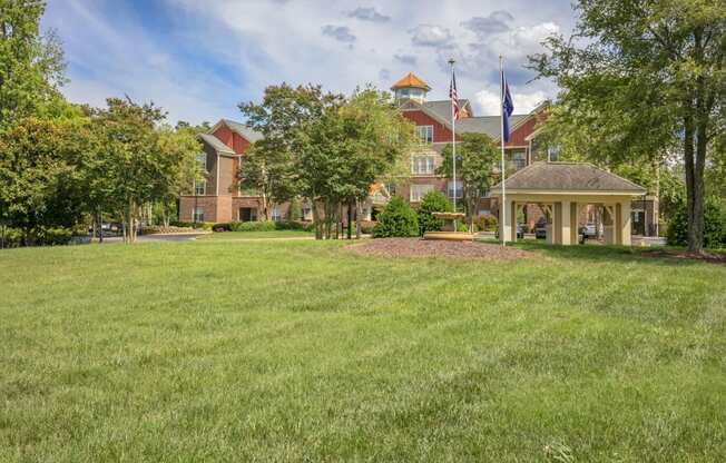 a large lawn with a gazebo and a building in the background