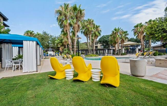 Outdoor seating and landscaping near pool and shaded tables Lunaire Apartments | Goodyear, Arizona