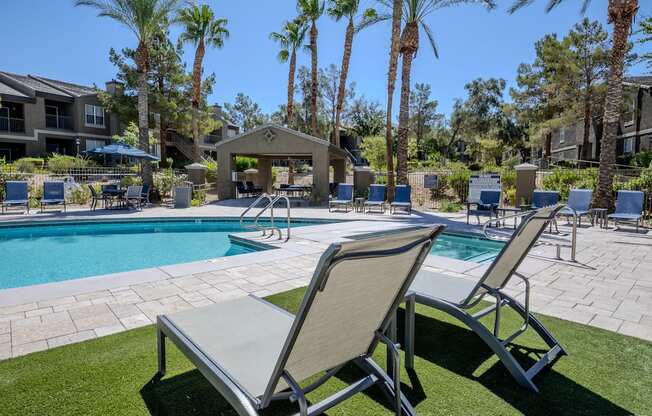 A poolside area with lounge chairs and palm trees.