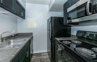 A black refrigerator and microwave in a kitchen.