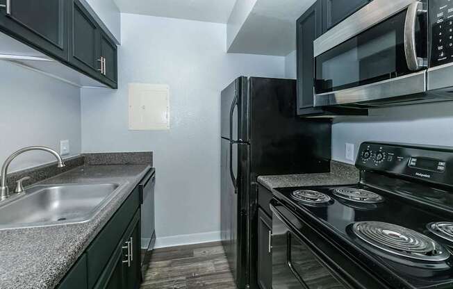 A black refrigerator and microwave in a kitchen.