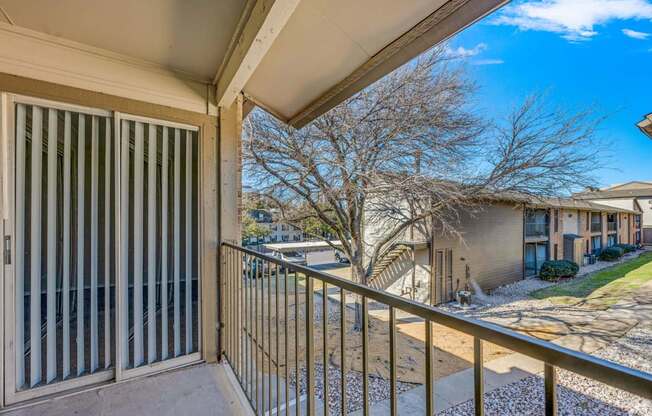 A balcony with a metal railing and a view of apartment buildings.