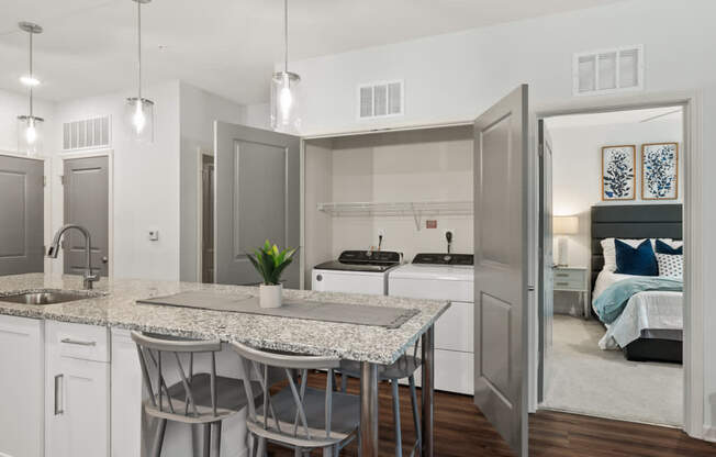 A modern kitchen with a marble table and a view into a bedroom.