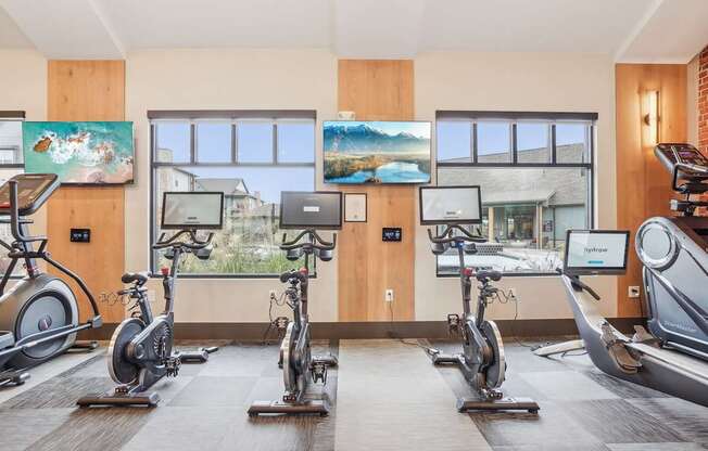 a gym with treadmills and exercise bikes in a room with windows