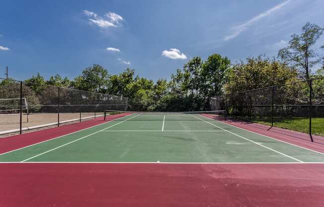 A tennis court with a red surface and green boundary lines.