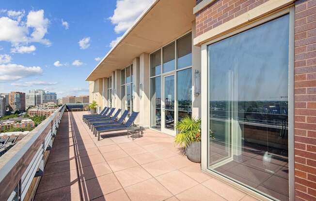A balcony with chairs and a table is on the roof of a building.