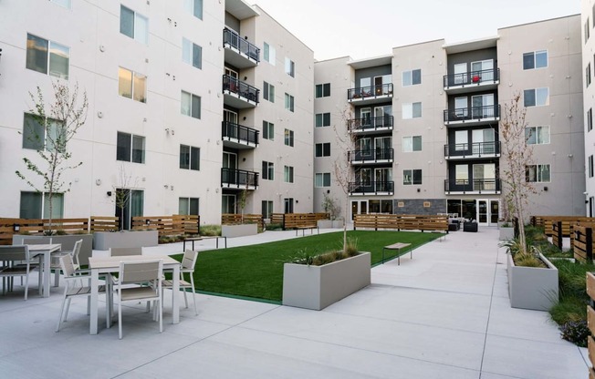 an outdoor area with tables and chairs in front of an apartment building